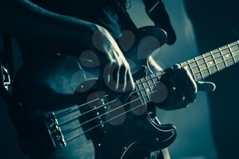Electric bass guitar player hands, live music theme, stylized green toned photo