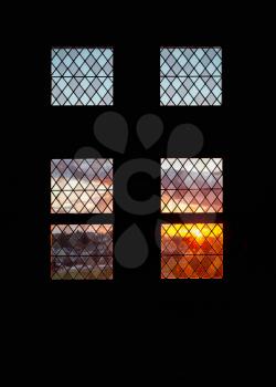 Colorful sunset pattern behind vintage window in dark stone wall