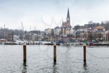 Flensburg town in winter, Germany. Coastal skyline with wooden mooring columns in water