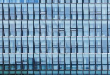 Modern office building facade with windows, blue toned glass and steel frames
