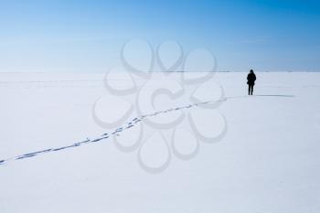 Lonely teenage girl walks along the endless snowfield