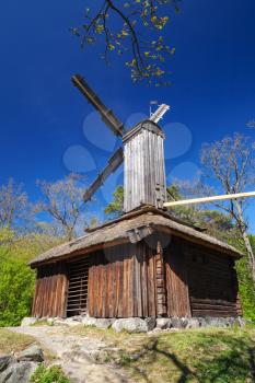 Wooden windmill under deep blue sky, vertical rural Swedish landscape