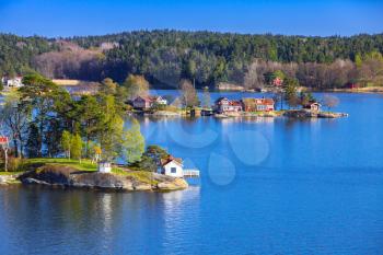 Rural Swedish landscape with coastal villages. Wooden houses and barns on islands in sunny summer day
