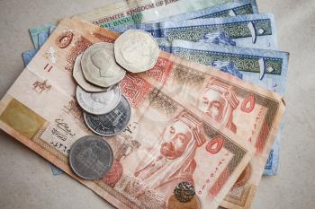 Jordanian dinars and piastres lay on gray paper background, close-up photo