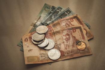 Jordanian dinars and piastres lay on gray paper background, close-up vintage stylized photo with tonal filter effect