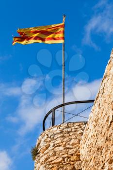 Flag of Catalonia waving on the wind above blue cloudy sky