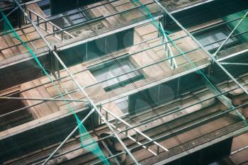 Old building facade under construction with green protective mesh