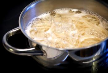 Boiling water with noodles in the steel pan