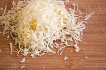 Pile of fresh grated cheese on wooden table