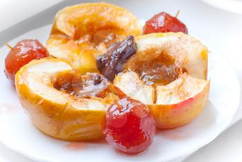 Baked apples with spices, honey and chocolate on white plate