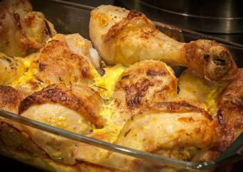 Chicken legs baked with mayonnaise spices and cheese in glass pan. Selective focus