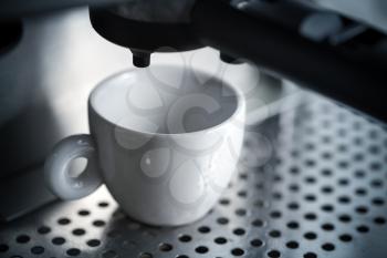 White ceramic cup in espresso coffee machine.