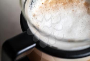 Closeup shot of milk foam on cappuccino in glass mug