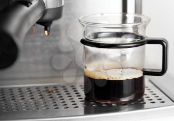 Modern glass cup of black coffee in espresso machine
