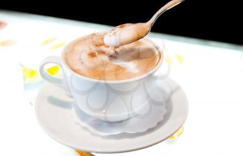 Cup of cappuccino with cinnamon on illuminated glass table