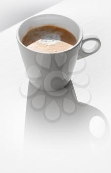 Cappuccino coffee in a ceramic cup on white table with shadow