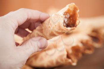 Homemade wafer cone with cream of sweet boiled condensed milk in man's hand. Traditional Russian dessert