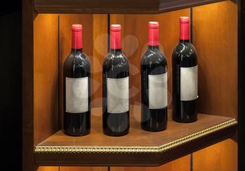 Four luxury red vine bottles on wooden shelf
