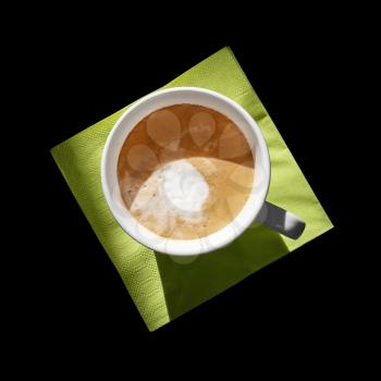Cappuccino coffee cup on green napkin isolated on black