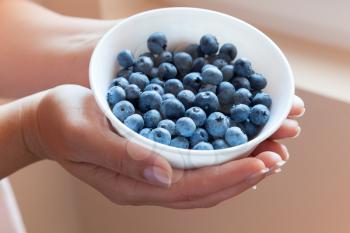Bowl of blueberries in woman's hands