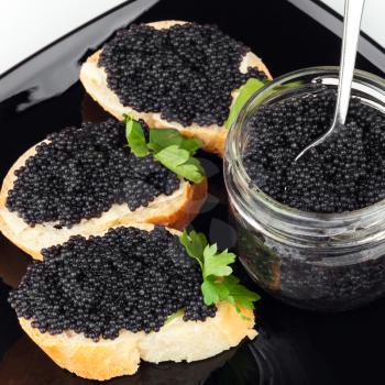 Sandwiches with black caviar on dark plate