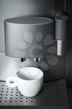 White ceramic cup stands in modern coffee machine