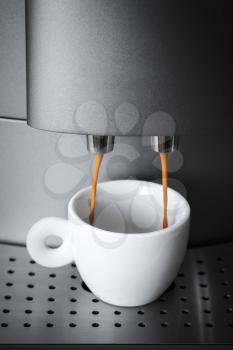 White ceramic cup in coffee machine, espresso preparing