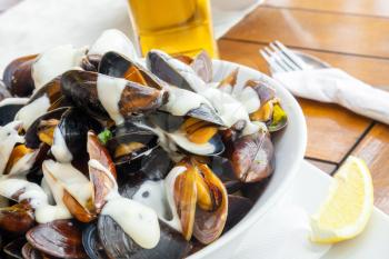 Plate full of mussels with garlic sauce on a table in restaurant 