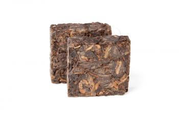 Two pressing briquette of black Chinese Shu Pu Erh tea stand isolated on white background, selective focus with shallow DOF