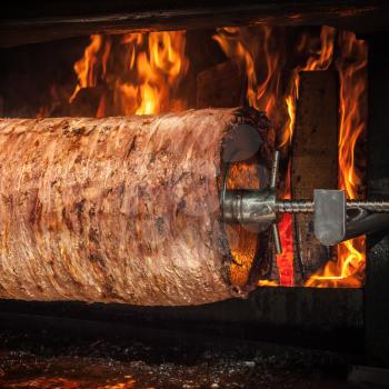 Traditional Turkish doner kebab is preparing in an oven with open fire, square composition