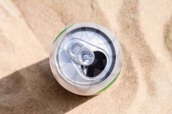 Aluminum can of beer stands on a beach sand