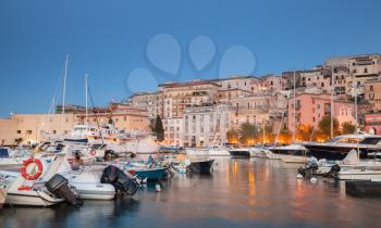 Port with moored motorboats and pleasure yachts. Night cityscape of Gaeta town, Italy