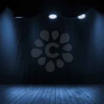 Dark blue scene interior with spotlights, wooden stage and fabric background