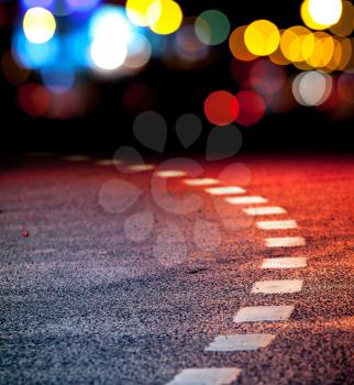 Turning asphalt road with marking lines and reflections with colorful unfocused lights on a background
