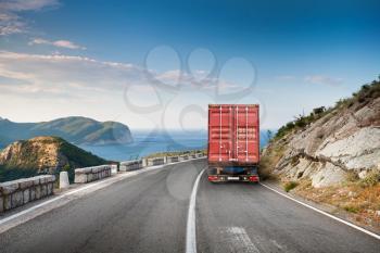 Cargo truck on the mountain highway with blue sky and sea on a background