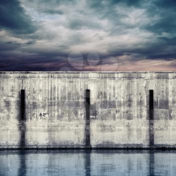 Abstract port fragment. Gray concrete mooring wall with dark stormy sky
