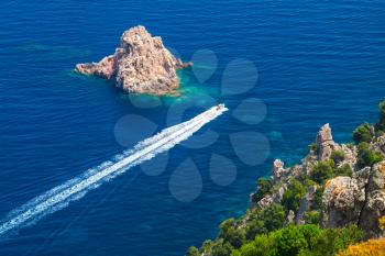 Fast motor boat goes between the stones of Capo Rosso, Piana region, South Corsica, France