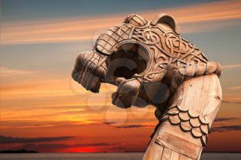 Carved wooden dragon on the bow of Viking ship above evening cloudy sky