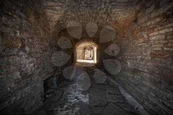 Old stone fortress dark stone tunnel perspective with glowing end