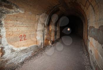 Dark abandoned tunnel interior perspective with glowing end. Petrovac town, Montenegro
