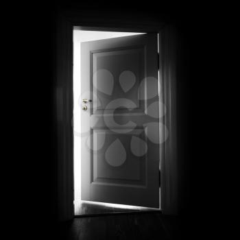 Opening white door in a dark room with light outside