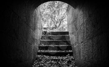 Exit with stairs from dark abandoned concrete tunnel interior