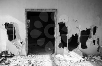 Abandoned building interior. Empty door and holes in wall. Black and white photo