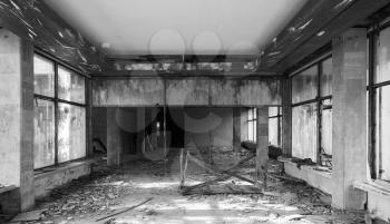 Abandoned building interior. Hall perspective with dirt on the floor and damages, monochrome photo