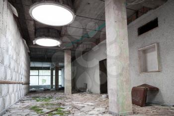 Abandoned industrial building interior. Green moss grow under round light holes in ceiling 
