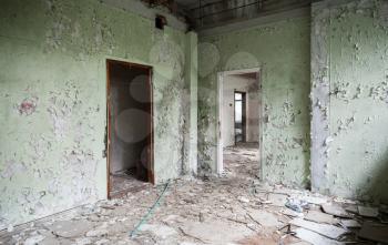 Abandoned industrial building interior. Cracked green walls with empty doorways