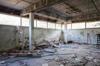 Abandoned industrial building interior. Hall with concrete columns and broken windows