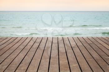 Wooden pier perspective with blue sea and pink sky on a background, photo with selective focus and shallow DOF