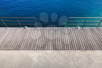 Wooden pier with metal railing, top view. Mediterranean Sea coast, Corsica island