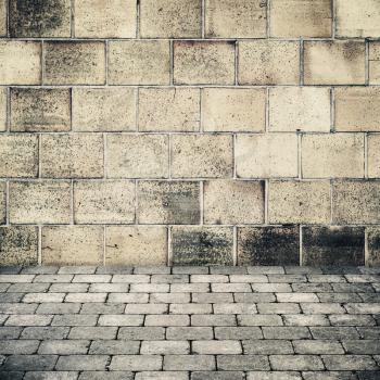 Empty abstract interior background with old stone wall and gray cobblestone pavement